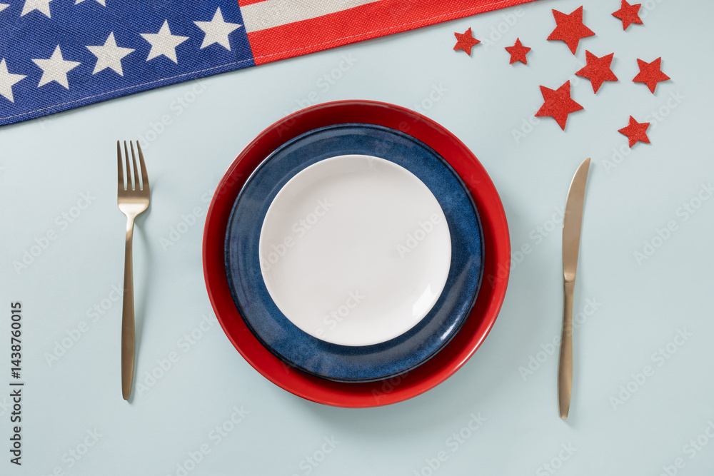 American table setting for USA Independence Day. Festive dinner with empty white plate and decoration in USA national flag colors red and blue. View from above. Copy space.