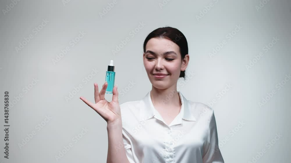 A positive young woman catches a cosmetic essential oil or facial serum. The concept of skin care and rejuvenation. A positive young woman catches a cosmetic essential oil or facial serum. The concept of skin care and rejuvenation.