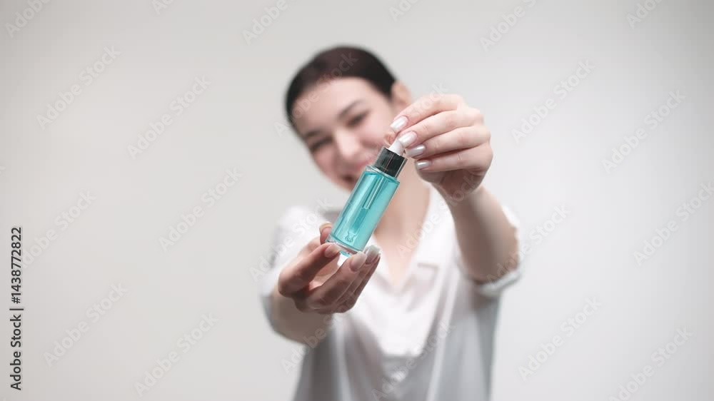 Pretty young woman holding out a bottle of skin care oil or anti-aging serum isolated on a white background to the camera. Concept of cosmetology and care products. Pretty young woman holding out a bottle of skin care oil or anti-aging serum isolated on a white background to the camera. Concept of cosmetology and care products.