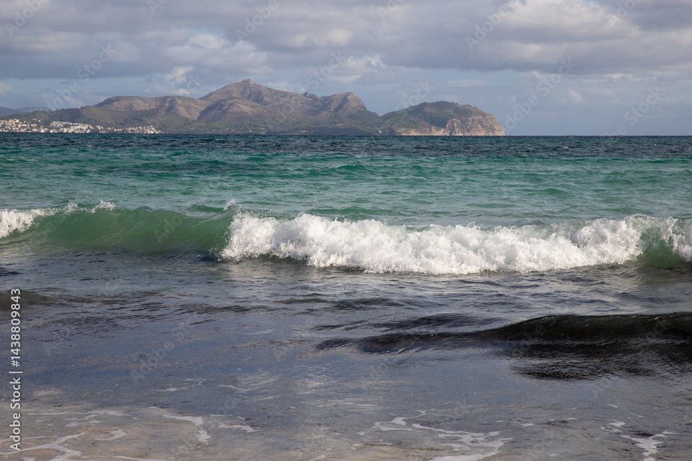 Mediterranean beach on the island of Majorca, or Mallorca on Balearic Sea, are part of Spain. Island in the Mediterranean Sea. Seaside vacations, clouds, seascape. View of the sea and the island. Mediterranean beach on the island of Majorca, or Mallorca on Balearic Sea, are part of Spain. Island in the Mediterranean Sea. Seaside vacations, clouds, seascape. View of the sea and the island.