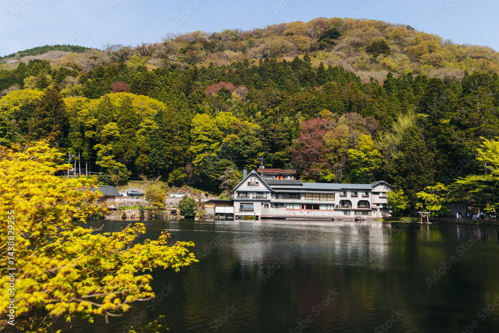Fototapeta premium Kinrin lake in Yufuin town, Kinrin-ko lake, Oita prefecture, Japan, hot spring onsen resort town, with mount Yufu, Kyushu island region, rural mountain landscape, a spring day with a blue sky