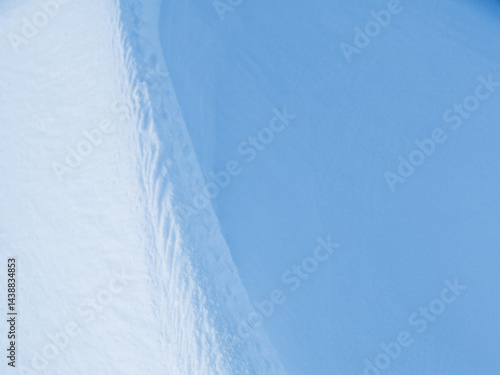 Snow texture. Wind sculpted patterns on snow surface. Wind in the tundra and in the mountains on the surface of the snow sculpts patterns and ridges (sastrugi). Arctic, Polar region. Winter background