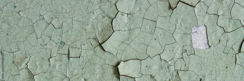 Peeling paint on the wall. Panorama of a concrete wall with old cracked flaking paint. Weathered rough painted surface with patterns of cracks and peeling. Panoramic texture for background and design.