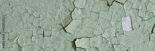 Obraz na płótnie Peeling paint on the wall. Panorama of a concrete wall with old cracked flaking paint. Weathered rough painted surface with patterns of cracks and peeling. Panoramic texture for background and design. w salonie