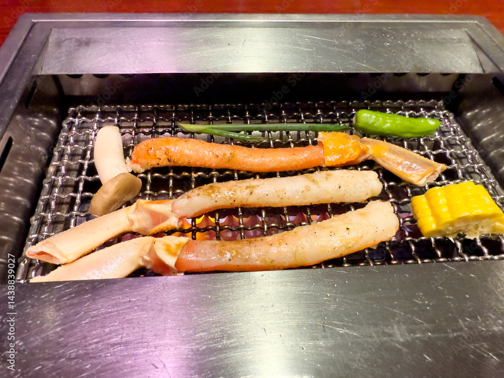 Close up of crab legs and vegetables being barbecued in grill
