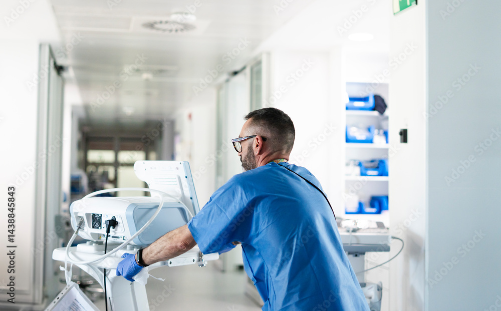 Fototapeta premium Doctor pushing medical equipment in hospital corridor