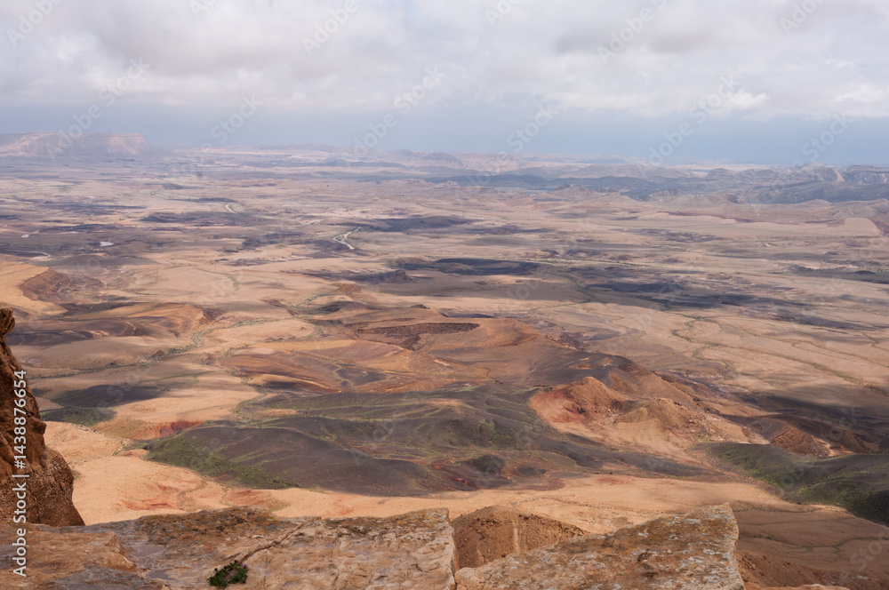 A desert landscape with a rocky outcropping in the foreground A desert landscape with a rocky outcropping in the foreground