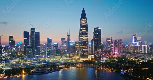 Aerial shot of illuminated modern city skyline with skyscraper reflecting on the water at night in Shenzhen, China.