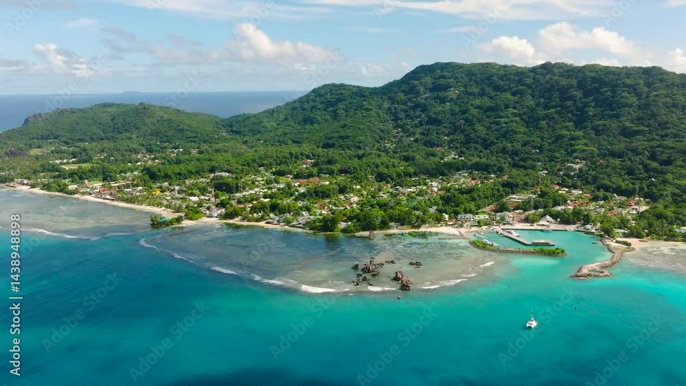 A scenic bay with lush greenery, coral reefs, and turquoise waters, bordered by hills. Seychelles, La Digue. A scenic bay with lush greenery, coral reefs, and turquoise waters, bordered by hills. Seychelles, La Digue.