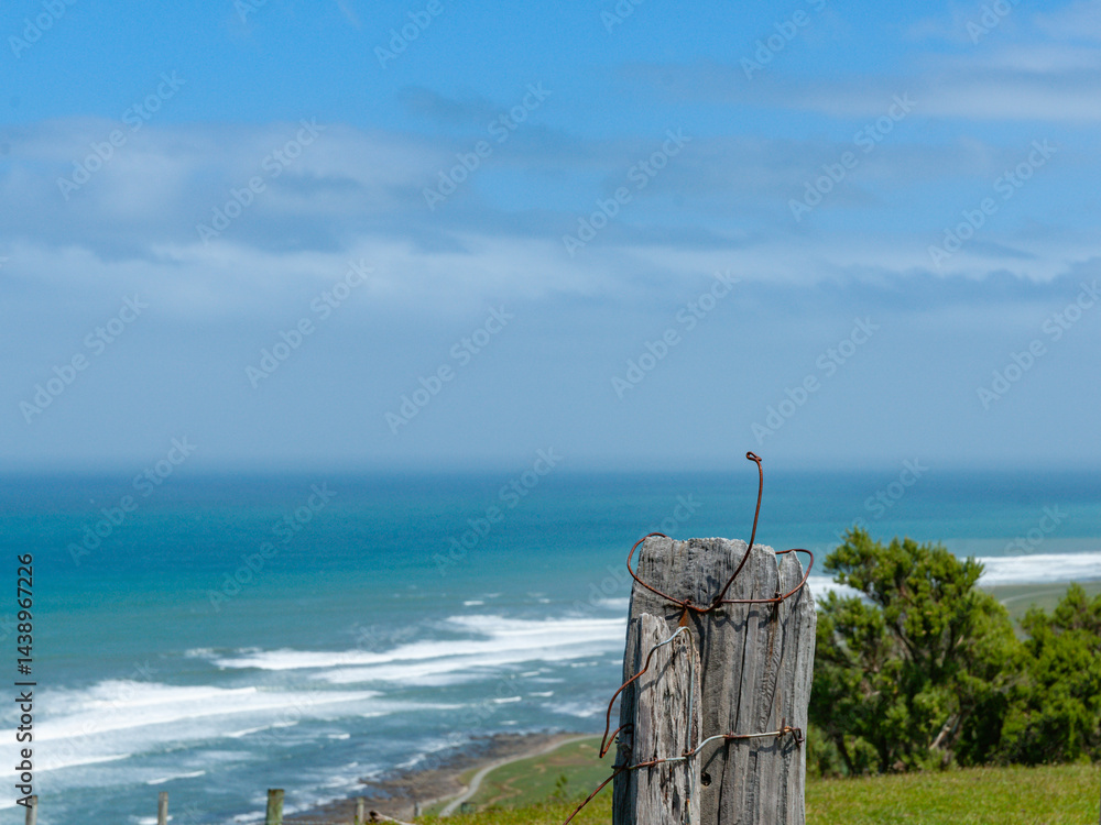 Old fence post and wire in foreground to wide coastal land and sea scene