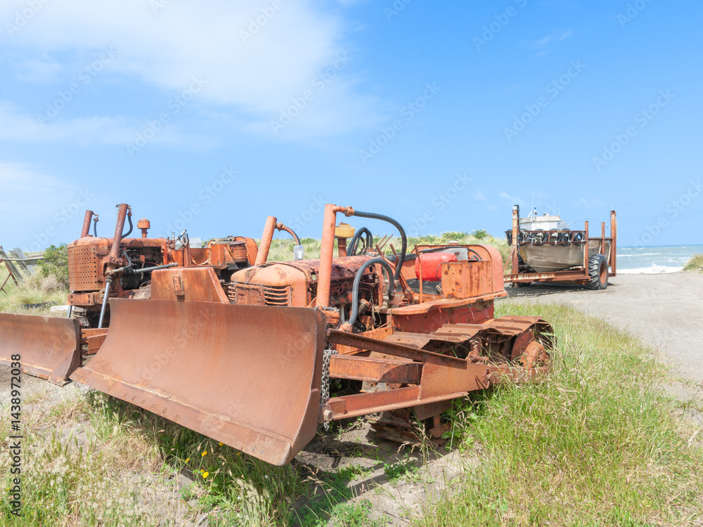 Old rusty bulldozers and fishing boat on trailer near beach
