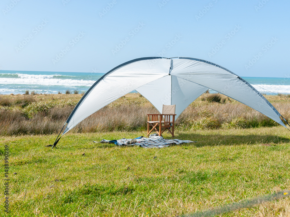 Sunshade erected on grass with beach background