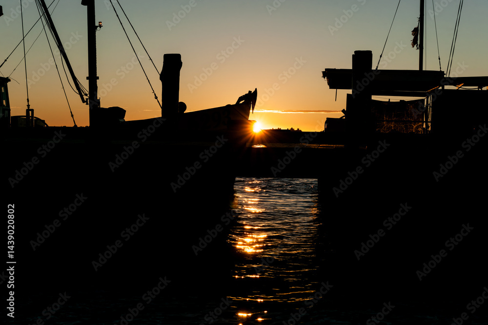 Fisherman’s wharf commercial boast in silhouette back-lit by sunrise