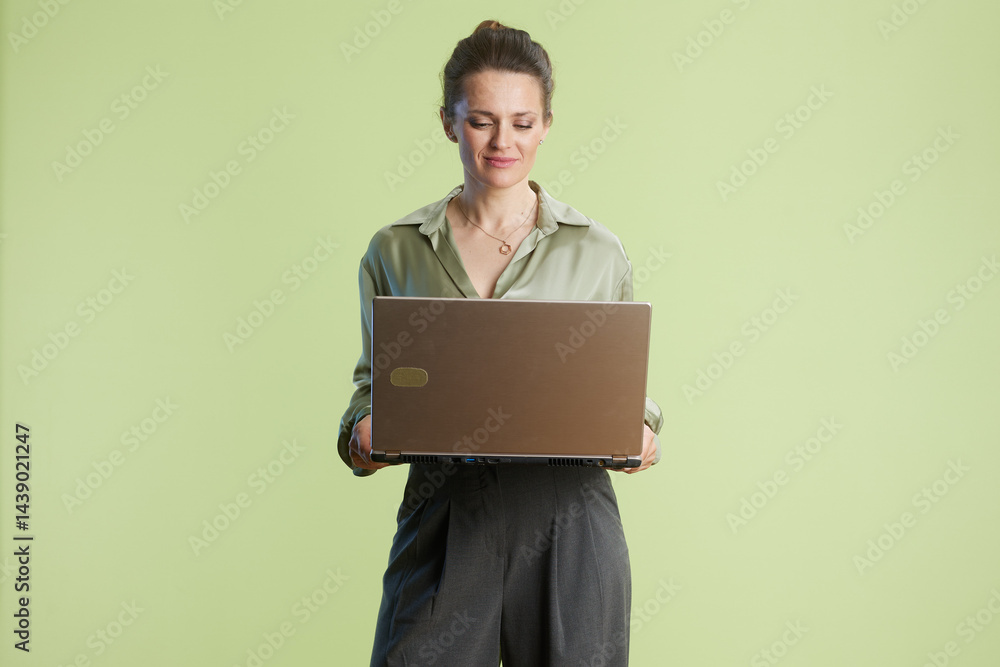 Woman in bright studio works on her laptop, focused