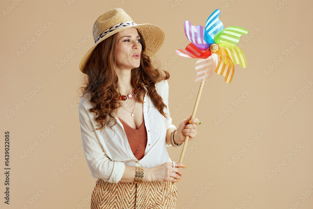 smiling trendy housewife in blouse and shorts against beige
