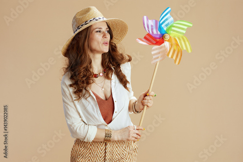 smiling trendy housewife in blouse and shorts against beige