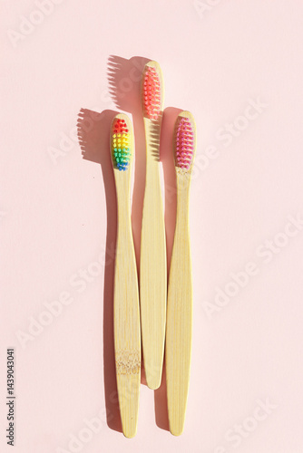 Obraz na płótnie Closeup Aesthetic Beige bamboo toothbrushes with colors bristles at sunlight on pink pastel background. Simplicity, hygiene, and environmentally friendly alternatives, top view photo, minimal flatly w salonie