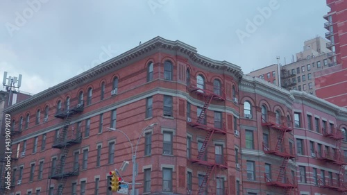 Close-up of a red-brick apartment corner building in New York City, featuring classic iron fire escapes and vintage architecture.