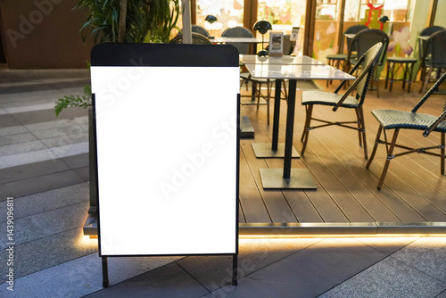 Blank white outdoor advertising stand sandwich board mock up template. Clear street signage board placed by an outdoor dinning area of a restaurant..