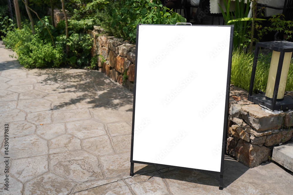 Blank white outdoor advertising stand sandwich board mock up template. Clear street signage board placed by an outdoor dinning area of a restaurant..