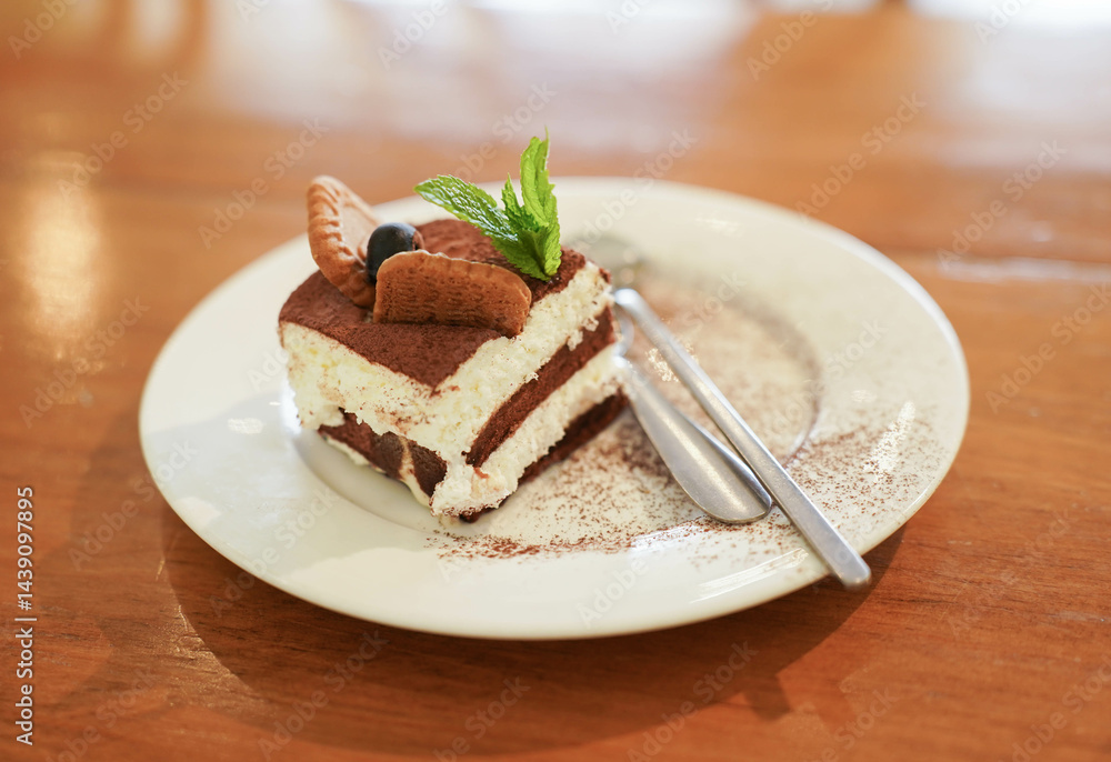 Tiramisu cake with mint leaf on wooden table