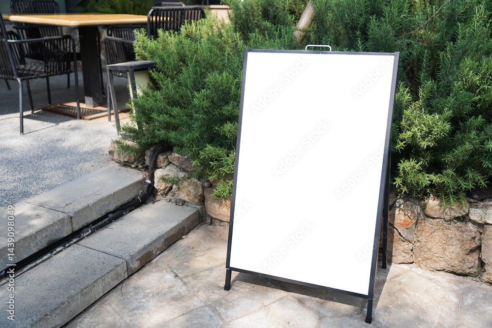 Blank white outdoor advertising stand sandwich board mock up template. Clear street signage board placed by an outdoor dinning area of a restaurant..