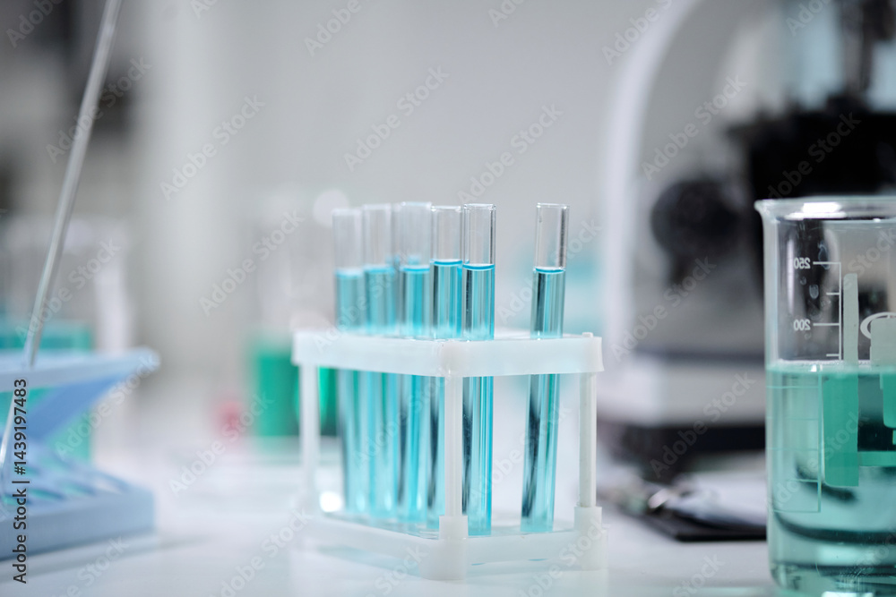 Laboratory equipment with several test tubes filled with a vibrant blue liquid. Beaker in the background along with a pipette can be seen, indicating a scientific experiment setting Laboratory equipment with several test tubes filled with a vibrant blue liquid. Beaker in the background along with a pipette can be seen, indicating a scientific experiment setting