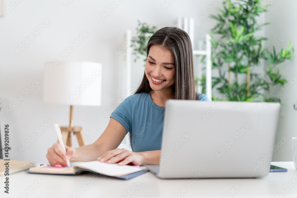 Asian attractive woman taking notes on book while learning from home. Asian attractive woman taking notes on book while learning from home.