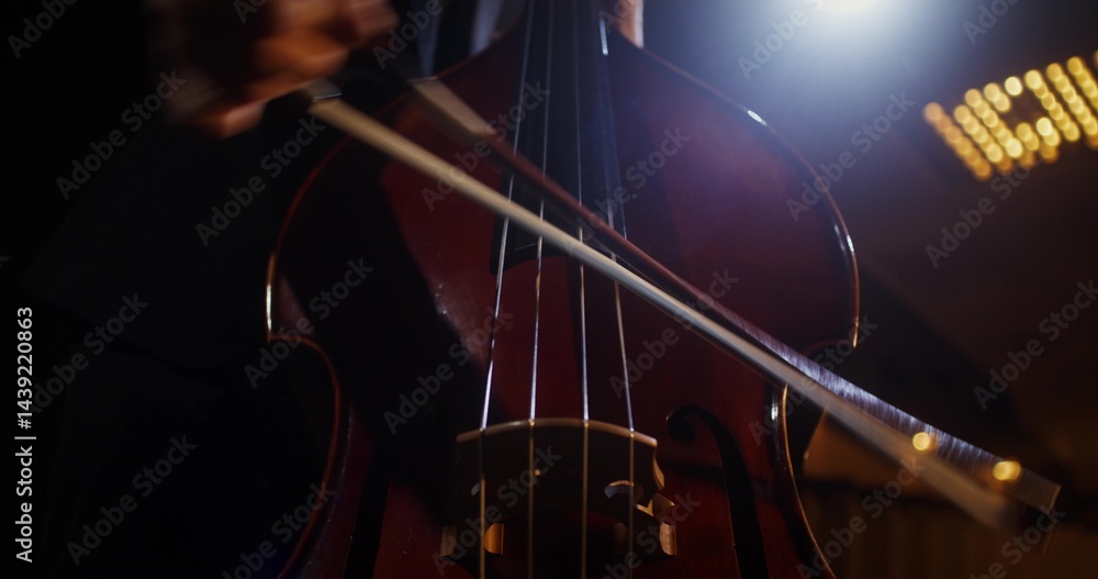 Fototapeta premium A man plays the double bass using a bow. Solo performance on the theater stage