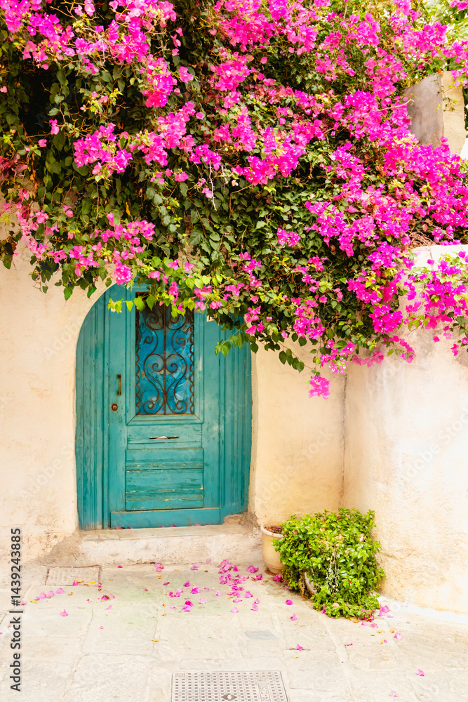 A stunning and beautiful blue door elegantly framed by vibrant bougainvillea, creating an enchanting picturesque scene. Rethymno town, Crete island, Greece.