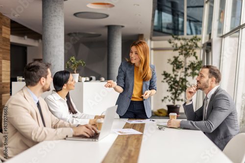 Fotografie Female chief standing at boardroom at corporate firm and discussing project with her employees