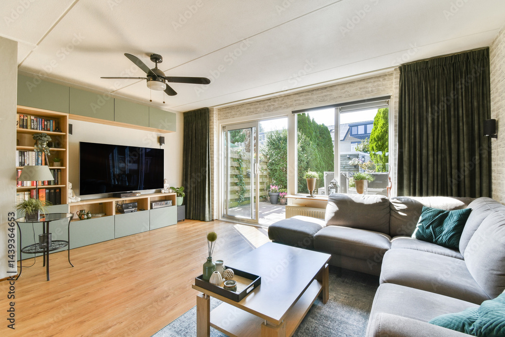 Fototapeta premium A stylish modern living room featuring a cozy sofa, sleek furniture, and large sliding glass doors that open to a lush garden view.