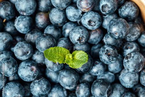 Obraz na płótnie Fresh blueberries with mint leaves on a wooden background in sunlight w salonie