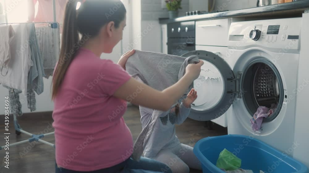 Pregnant Mother and Daughter Bond While Doing Laundry at Home Pregnant Mother and Daughter Bond While Doing Laundry at Home
