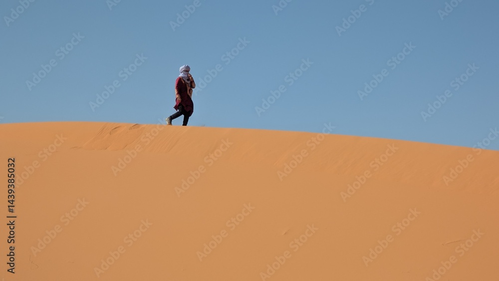 Person wandert auf einer Sanddüne in der Wüste Sahara Person wandert auf einer Sanddüne in der Wüste Sahara