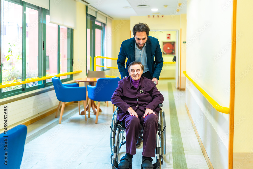 Nurse pushing smiling senior woman in wheelchair through nursing home corridor