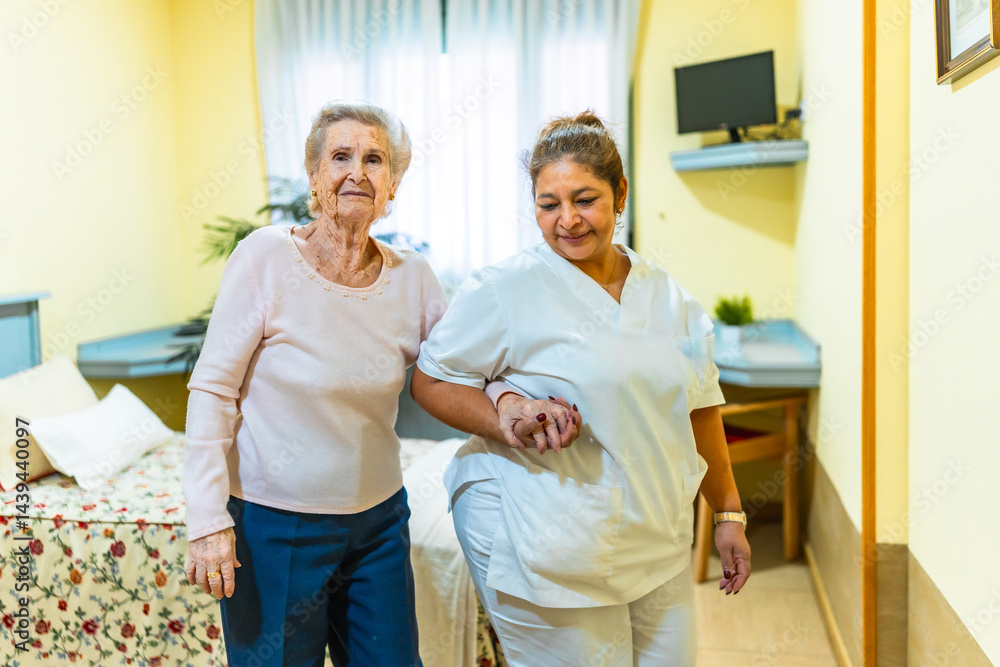 Fototapeta premium Nurse assisting elderly woman walking in nursing home