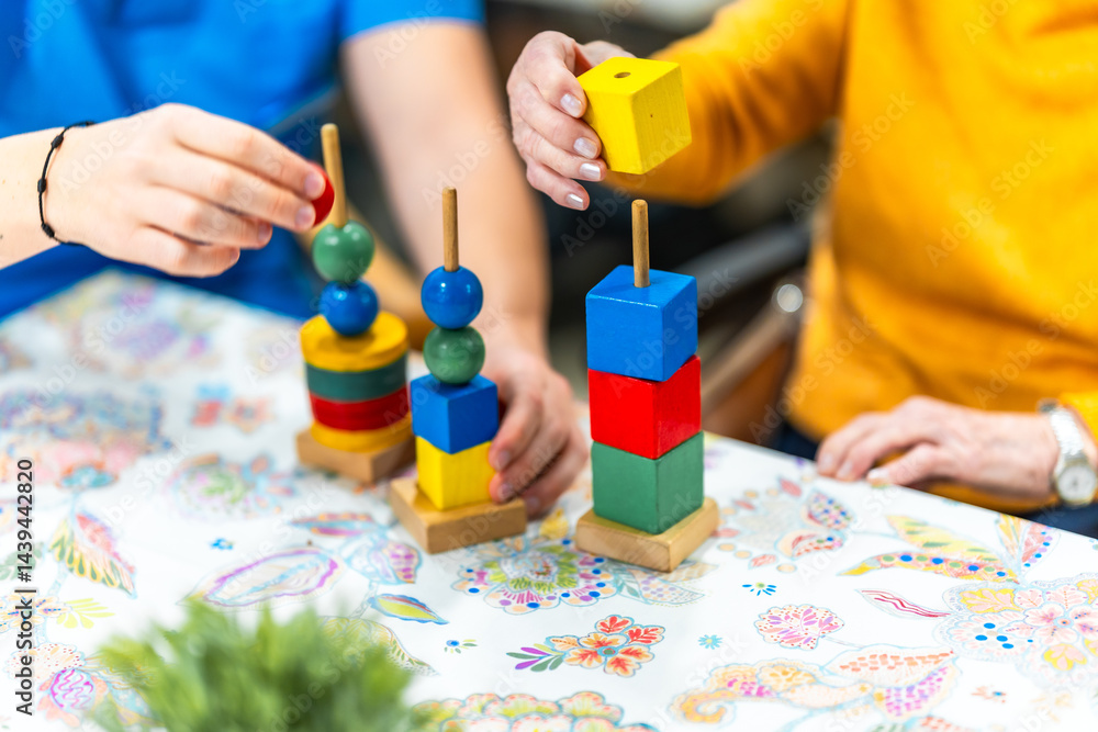 Nurse and patient playing with colorful wooden toys in nursing home