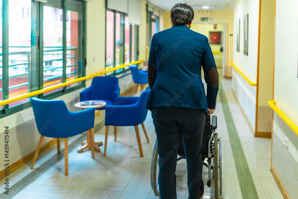 Doctor pushing empty wheelchair in nursing home corridor