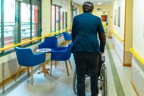 Obraz na płótnie Doctor pushing empty wheelchair in nursing home corridor w salonie