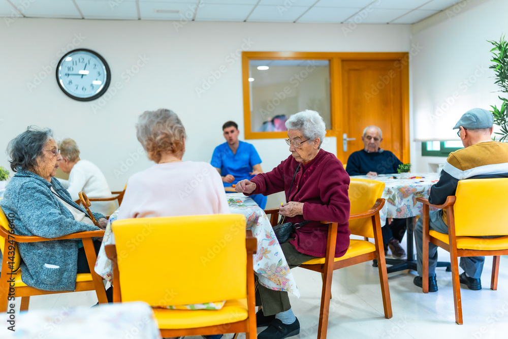 Elderly people playing cards and socializing in nursing home