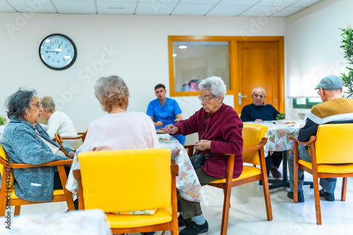 Elderly people playing cards and socializing in nursing home