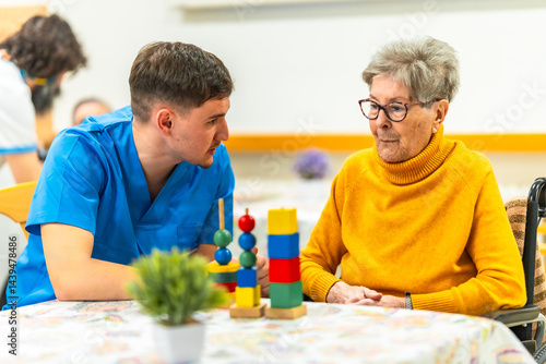 Male nurse assisting elderly woman with cognitive games in nursing home