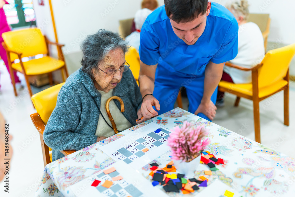 Male nurse assisting elderly woman playing bingo in nursing home