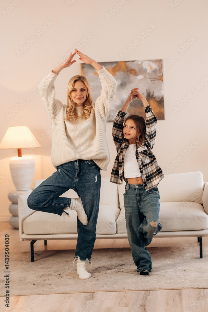 Naklejka premium Standing on one leg, sport and yoga. Mother and daughter are together in domestic room