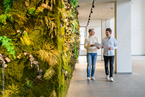 Two men having a business discussion in an office with a green wall