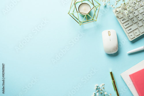 Obraz na płótnie Office table with keyboard, notebook, pen and flowers on blue background. Top view with copy space. w salonie