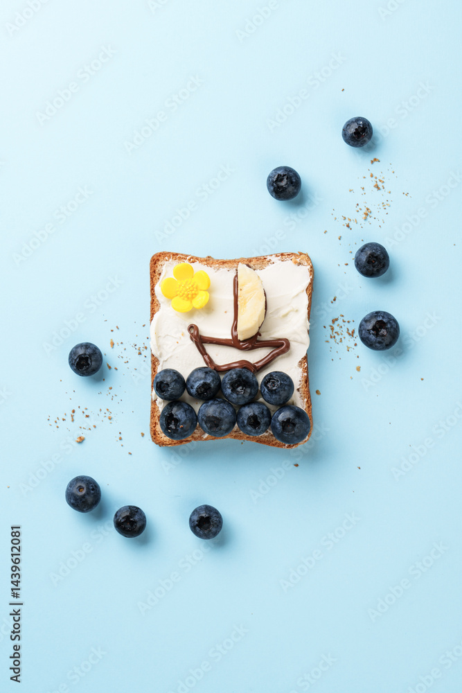 Open sandwich with funny pictures on it. Toast with blueberry and chocolate paste.