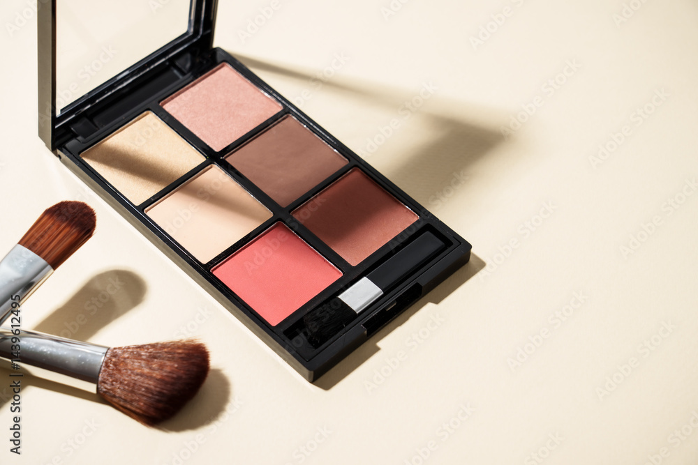 Make up palette and cosmetic brushes at pastel background with hard shadows.
