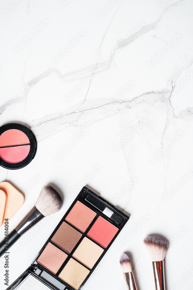 Make up products at white marble background. Cosmetic palette, brushes and lipsticks. Top view with copy space.